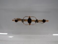 A hallmarked 9 carat gold bar brooch set with garnet and seed pearl -one seed pearl missing