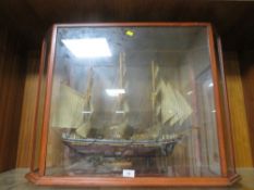 A model of a tall sail ship in a bespoke glass display case