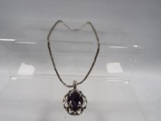 A decorative silver pendant on chain set with a purple stone