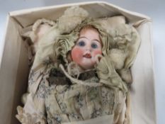 A small vintage bisque head doll in period clothing, indistinct marks to nape of neck
