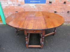 AN EARLY 19TH CENTURY OAK DROPLEAF GATELEG TABLE, having two frieze drawers, raised on turned