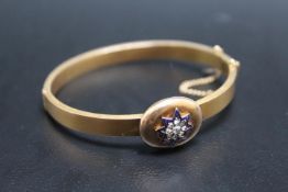 A 15CT DIAMOND AND ENAMEL BANGLE, having a central diamond surrounded by 8 diamonds and these in