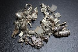 A HEAVY SILVER CHARM BRACELET, festooned with many charms, approx weight 107.6g