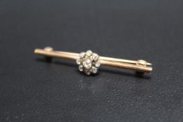A DIAMOND 'FLOWER' BAR BROOCH, the diamonds on a rub over setting on unmarked yellow metal brooch,