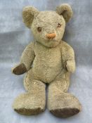 AN EARLY / MID 20TH CENTURY TEDDY BEAR, glass eyes, stitched nose and mouth, velvet paw pads,