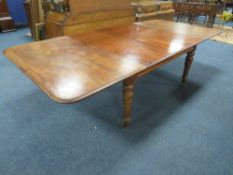 A MID-VICTORIAN MAHOGANY PULL-OUT EXTENDING DINING TABLE, having three additional leaves, raised