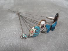 FOUR ENAMEL EMBELLISED HATPINS, to include a hallmarked sliver Charles Horner example, together with