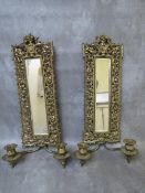 A PAIR OF EARLY 20TH CENTURY BRASS PIERCED MIRRORED WALL SCONCES, each with a pair of candle