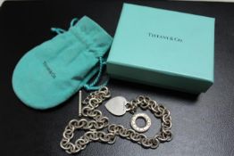 A SILVER TIFFANY & CO NECKLACE CHAIN WITH HEART AND CIRCULAR PENDANTS AND T BAR, complete with a box