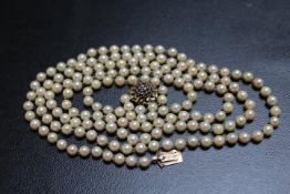 A LONG STRAND OF INDIVIDUALLY KNOTTED FRESHWATER CULTURED PEARLS ON A DOMED 9ct GARNET SET