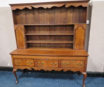A 19TH CENTURY OAK COUNTRY DRESSER, having an enclosed plate rack with two crossbanded cupboards,