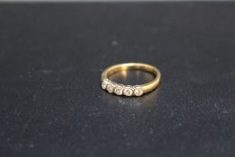 AN 18 CARAT GOLD FIVE STONE DIAMOND RING, in a rub over setting, approx weight 3.1g, ring size O