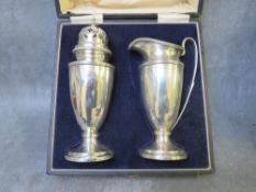 A CASED HALLMARKED SILVER STRAWBERRY SET, comprising a tall cream jug and sugar sifter, Birmingham