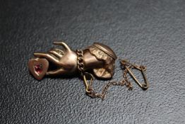 A NOVELTY BROOCH IN THE FORM OF A LADY'S HAND WEARING A GOLD CHAIN AND A DIAMOND RING HOLDING A