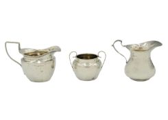 Two silver cream jugs and a twin-handled sugar bowl.
