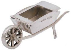 An Edwardian silver novelty stamp box in the form of a wheelbarrow.