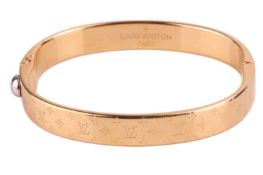A Louis Vuitton bangle, gold plated with an LV monogram engraved on a flat cross-section hinged two-