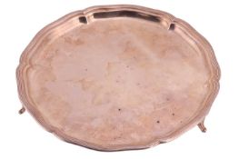 A silver salver, of plain circular form with a shaped rim raised on three pad feet, by William Hutto
