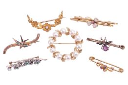 A collection of seven brooches; including an emerald and diamond brooch with a foliate design measur