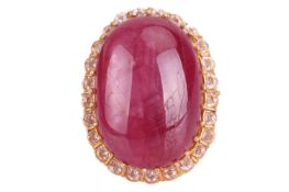 A cabochon ruby and cubic zirconia cluster ring; the oval ruby claw mounted within a band of round b