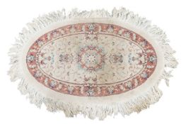 An ivory ground oval Tabriz rug with a central boss with a floral design within a fruiting vine bord