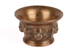 An early 17th century Continental mortar, with repeating mask decoration, 6.5 cm high x 10.5 cm wide