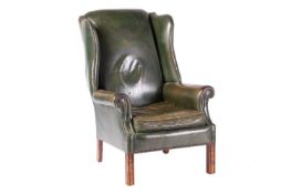 A George III-style wingback fireside chair with close nailed aged bottle green hide stuff over uphol