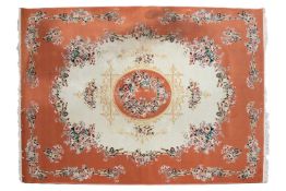A machine woven ivory ground Tabriz style carpet with circular central boss and a salmon pink border