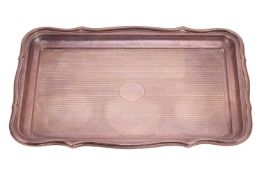 An Edwardian silver dressing table tray, shaped rectangular with raised scrolling borders and engine