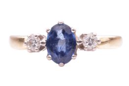 A sapphire and diamond three stone ring, the central oval sapphire measuring 7 x 5 x 3mm, between ro