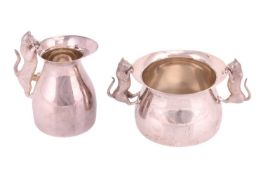 A novelty silver sugar and cream jug, low bellied, the handles formed as cast cats peeking over the 