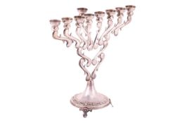 A Hanukkah menorah, a candelabrum with nine branches, in scrolled design, supported on three bracket