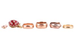 Four wedding rings and two charms; to include an 18ct yellow gold plain wedding band, size M; a simi