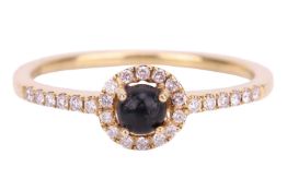 A Whitby jet and diamond halo ring in 18ct yellow gold, consisting of a round jet cabochon within a 