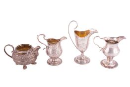 Three silver cream jugs and a milk jug; to include a George III stemmed cream jug with repoussé work