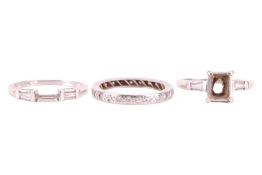 A diamond set ring mount; the central vacant aperture for a baguette cut diamond and flanked by sing