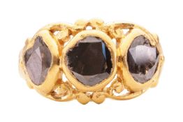 A three stone high carat gold ring, featuring three rub-overset faceted black diamonds in 18ct+ gold