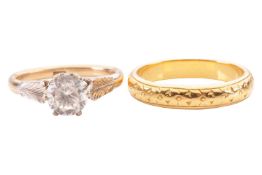 A 22ct yellow gold wedding band, together with a CZ set single stone ring. The textured band has ful