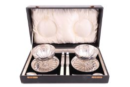 A cased grapefruit set, comprising two silver bowls with flare bases and fluted decoration resemblin