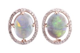A pair of opal and diamond halo stud earrings in 9ct yellow gold, each centred with an oval tablet o