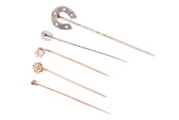 A collection of five stick pins. To include a rose cut diamond horseshoe stick pin testing at 9ct go