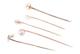 A collection of five gem-set stick pins; to include a trefoil clover motif pin set with seed pearls 