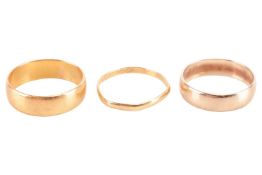 Three yellow metal rings comprising a 9ct gold wedding band, an 18ct gold wedding band, and a 22ct g