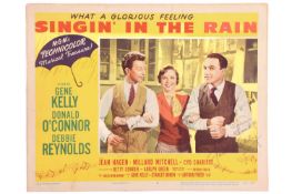An original 'Singin' In The Rain' 1952 signed lobby card (#2), bearing the signatures of Gene Kelly,