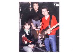 The Jam / Paul Weller: a colour photograph of the group, signed in black marker by Paul Weller, 25.5