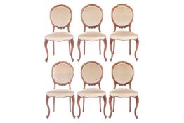 A set of six Victorian walnut dining chairs, the upholstered oval backs with flowerhead carving abov