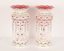 A pair of early 20th century milk glass cased and cranberry glass table lustres with printy and slas