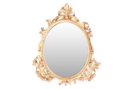 A Victorian carved wood and gilt gesso oval wall mirror flanked with leafy scrolls and moulded borde