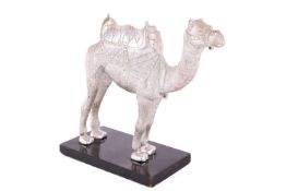 An Omani camel ornament, modelled as a camel with saddle on hump, base metal, attached to a wooden b