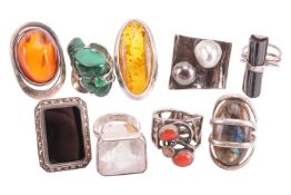 A collection of gem-set rings in silver and white metal mounts, including two bezel-set amber rings,
